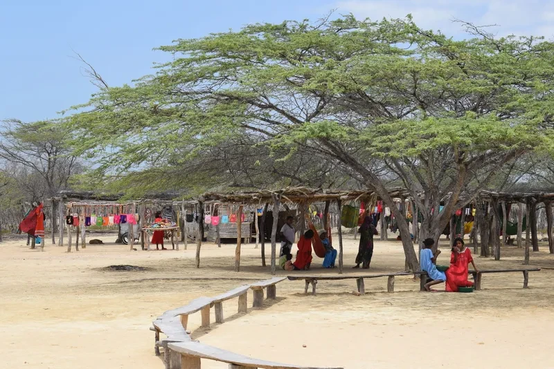 Puestos artesanales al aire libre con mujeres Wayuu y mochilas exhibidas