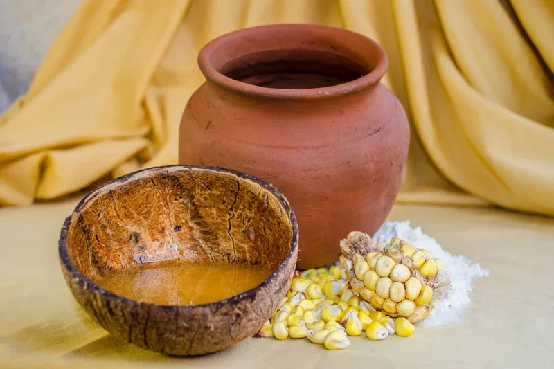 Chicha de maíz servida en totumo junto a mazorca fermentada y vasija de barro