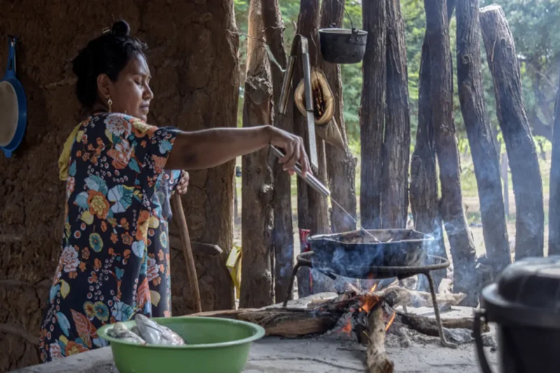Mujer wayuu cocinando en fogón de leña dentro de una ranchería tradicional
