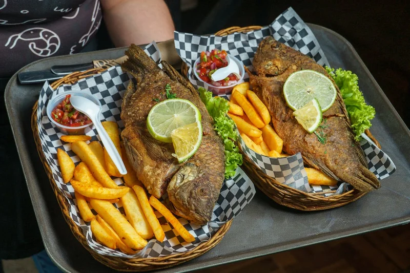 Pescado fresco frito servido con acompañantes en experiencia gastronómica costera