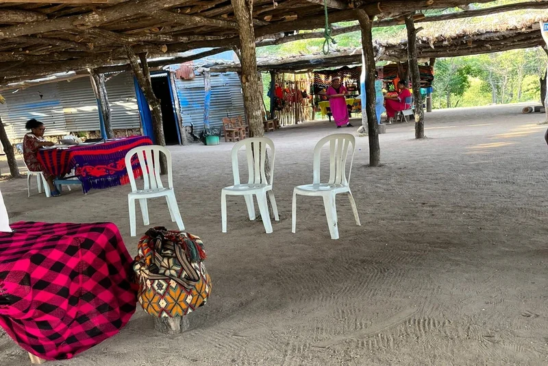 Espacio comunitario en ranchería con sillas, mochilas y venta artesanal