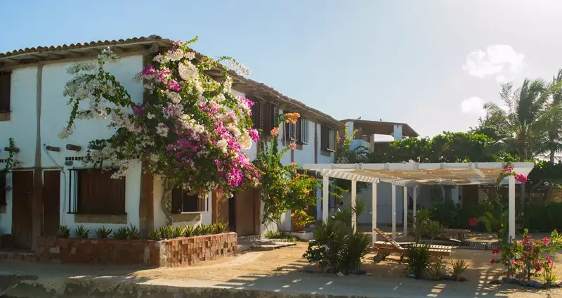 Fachada de hostal rural en La Guajira con jardines y áreas de descanso al aire libre