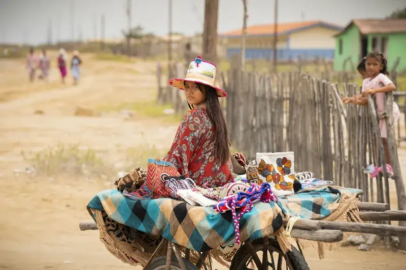 Mujer wayuu ofreciendo mochilas artesanales en zona rural de La Guajira