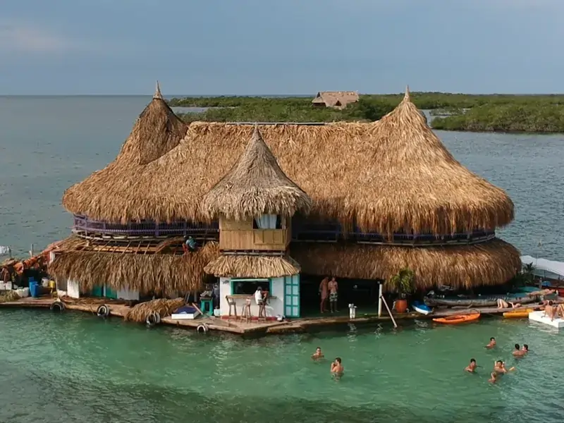 Hostal palafítico con techos de palma sobre aguas turquesa en la costa de La Guajira