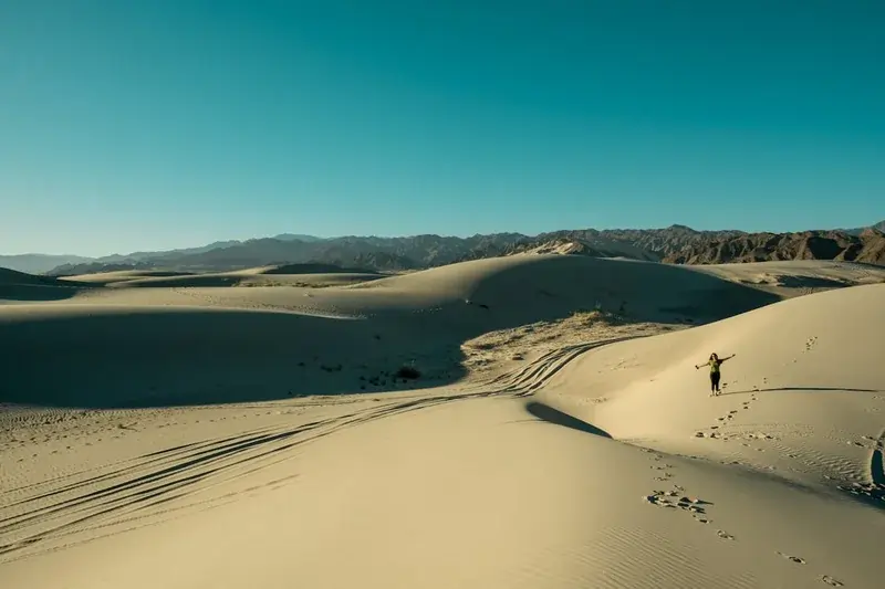 Persona caminando sola entre dunas extensas bajo el sol en Punta Gallinas