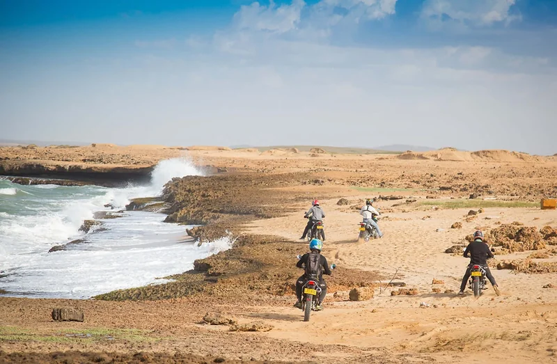 Grupo de motociclistas recorriendo la costa arenosa hacia playas escondidas en La Guajira