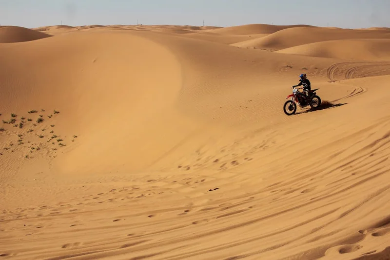 Motociclista atravesando dunas de arena en un terreno extremo de La Guajira