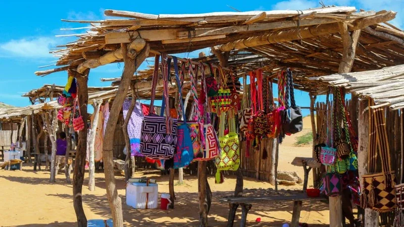 Puesto artesanal wayuu con mochilas coloridas en un mercado local de La Guajira