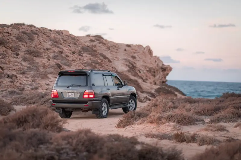 Vehículo 4x4 de agencia turística avanzando en carretera desértica junto al mar en La Guajira