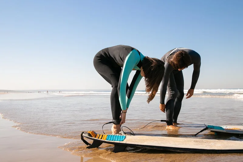 Dos personas ajustando el equipo antes de una clase de deportes acuáticos en la playa