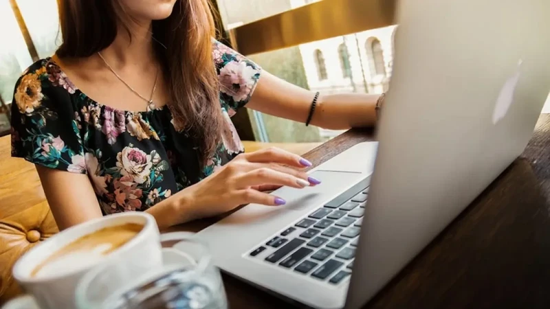 Mujer trabajando en laptop desde cafetería con buena señal y ambiente tranquilo