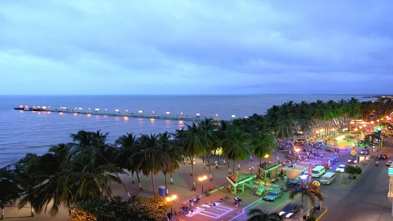 Vista del malecón y muelle de Riohacha iluminados en la noche con ambiente urbano seguro
