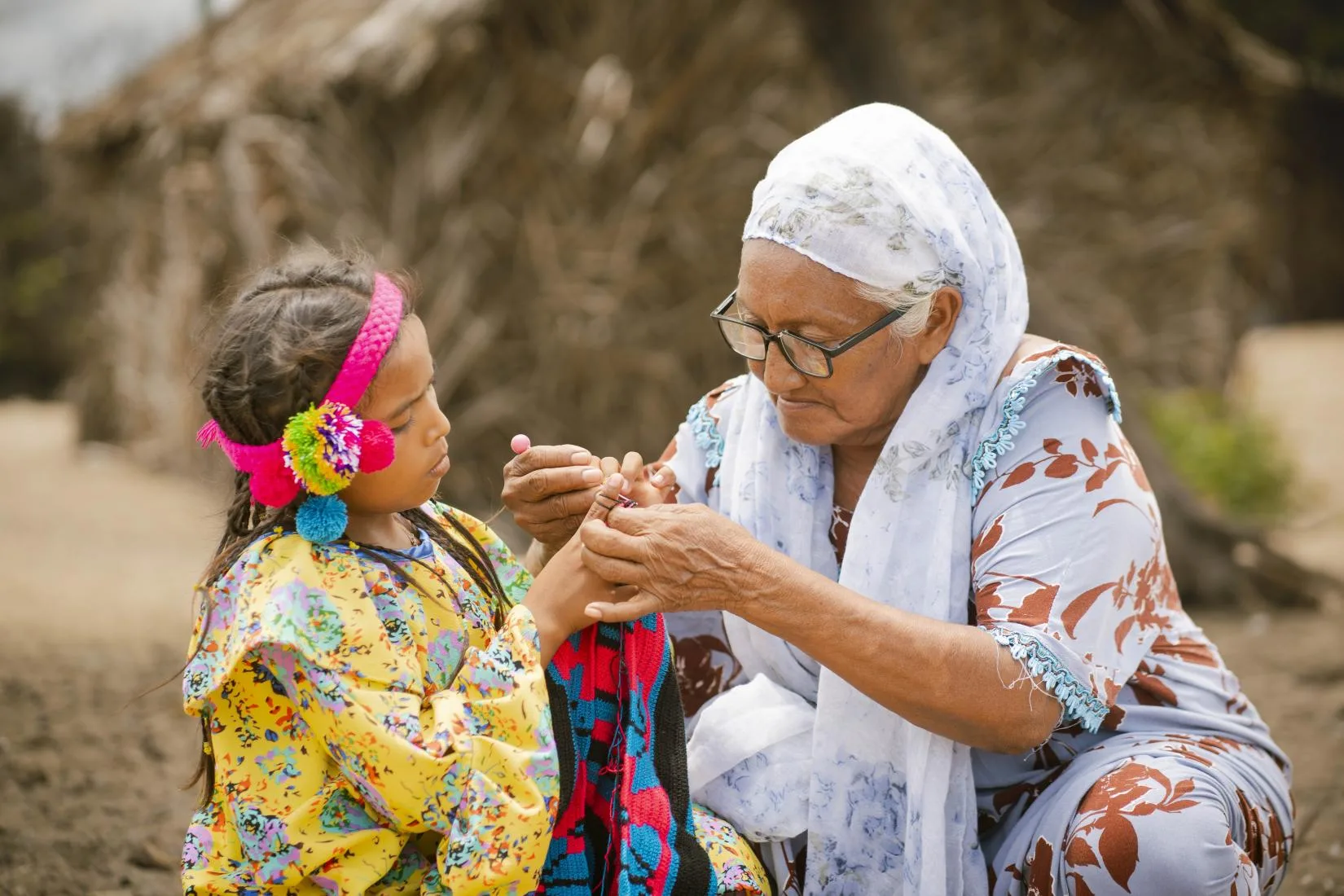 Abuela Wayuu enseñando a su nieta a tejer una mochila tradicional