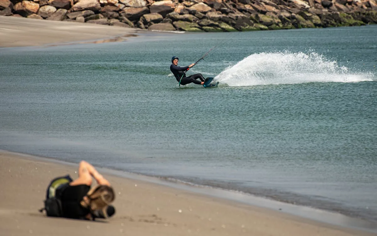 Deportista practicando kitesurf en playa tranquila con fondo rocoso en La Guajira